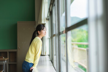 教室の中から窓の外を見ている女子小学生