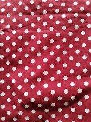 Red fabric in polka dots pattern background. Modern textile texture. Detail of clothing. Christmas concept. © Endri miswono