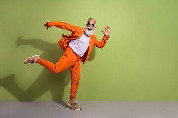 Full size photo of funny extravagant man dancing running empty space wear orange suit isolated on...