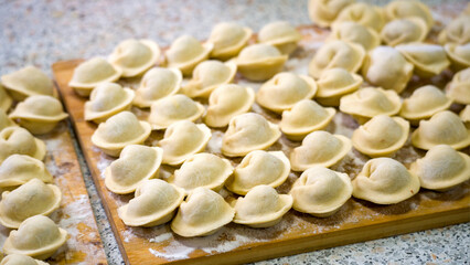 Homemade dumplings close-up. handmade dumplings on a wooden board, selective focus, tinted image, traditional Russian dish,