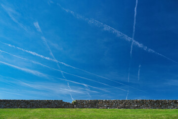 Kent, UK - September 14, 2024:  Contrails drawn on blue sky over Dover strait
