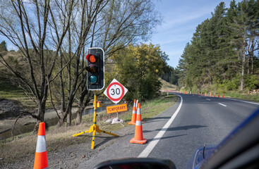 Temporary traffic light control on the side of the road. Cars stopped at the roadwork red light....