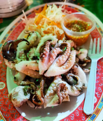 Plate of octopus with a fork and a container of sauce