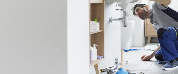 Professional repairman checking a leaking bathroom sink