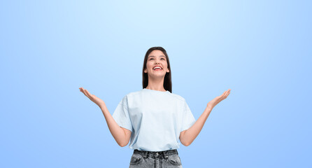 Happy person in casual clothes raising hands against light blue