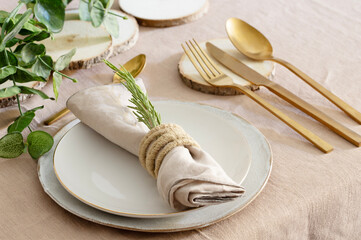 Table setting for elegant festive dinner with white porcelain plates, glass, green napkin, gold...