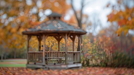 Soft focus of a fall park with blurred gazebo and foliage under a cloudy sky