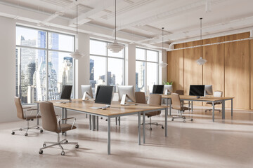 Stylish coworking interior with pc computers in row, panoramic window