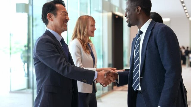 ロビーで握手する多国籍ビジネスパーソンのグループ