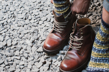 Man is putting on a pair of brown full grain leather shoes boots at outdoor with stone floor, Trying shoes leather boots.