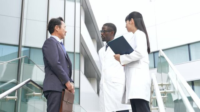 ロビーで会話するビジネスマンと白衣の多国籍技術者グループ