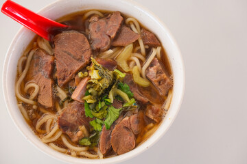 A bowl of delicious Malaysian beef noodle with soup on the table.