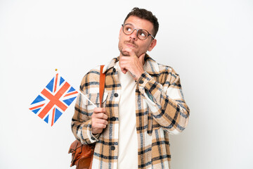 Young hispanic man holding an United Kingdom flag isolated on white background and looking up