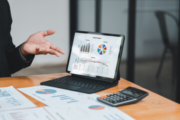 A professional business presentation featuring financial charts on a tablet, documents, and a calculator on a wooden desk.