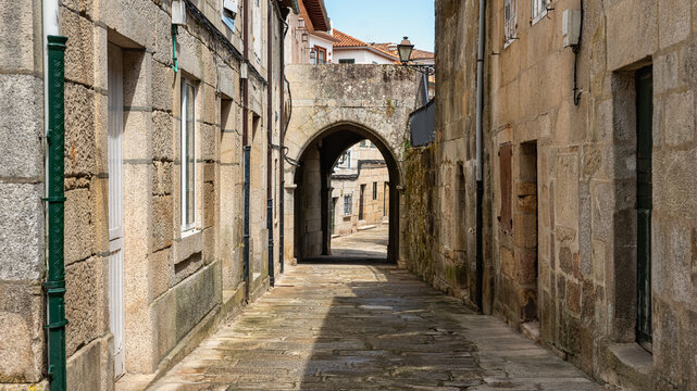 Fototapeta Old stone houses with arches and passageways dividing the streets in the medieval town of Tui, Galicia.