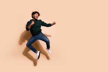 Full size photo of nice young man jump fight empty space wear sweater isolated on beige color...