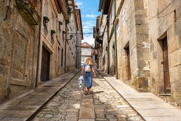 Tourist woman climbing the steep streets of the medieval town of Tui in Galicia.