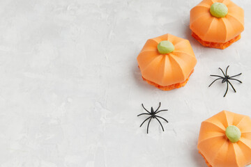 Three orange pumpkin shaped treats with green tops, accompanied by small black spider decorations