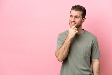 Young caucasian man isolated on pink background looking to the side and smiling