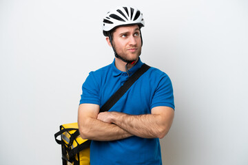 Young caucasian man with thermal backpack isolated on white background making doubts gesture while lifting the shoulders