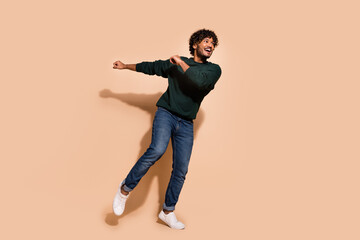 Full size photo of nice young man dancing partying wear sweater isolated on beige color background