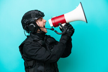 SWAT caucasian man isolated on blue background shouting through a megaphone