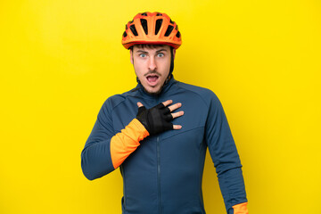 Young cyclist caucasian man isolated on yellow background surprised and shocked while looking right