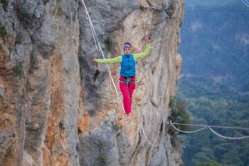 A tightrope walker walks along a cable stretched over a canyon.