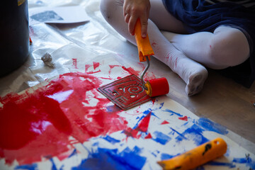Children creating lino cut prints on paper using rollers, paint, and spoons in an art workshop. Creativity, craft techniques, and artistic expression, educational and creative stock imagery.