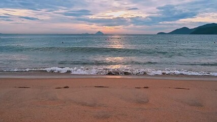 Sandy beach by the sea with waves in the morning at sunrise in summer at a tropical resort