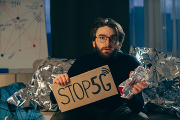 Conspiracy theory concept. A man holds a sign with a pseudoscientific slogan.
