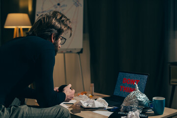Shaping Worldview: Man Stares at Laptop Screen with 'Don't Think!' Message