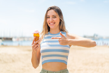 Young pretty woman with a cornet ice cream at outdoors and pointing it