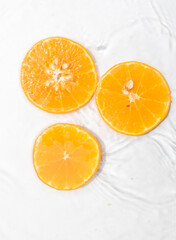 Juicy slices of orange fruit suspended on water ripples, creating a natural and refreshing scene.