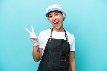 Fishwife Argentinian woman isolated on blue background smiling and showing victory sign