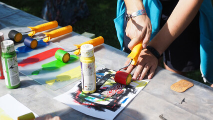 Participants at a summer festival outdoor lino cut workshop creating custom prints and temporary tattoos. Engaging in hands-on art activities, they carve designs, print on paper.