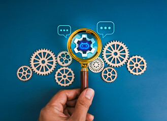 AI searching tools, robot job business service, development and management technology concept. Chat bot icon in magnifying glass lens in hand decoration with many gear and cogwheel, blue background.