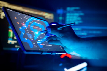 Programmer manually working with program code on a computer at night in a data center and...
