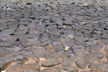 A dark, textured pattern formed by a collection of rough, uneven stones
