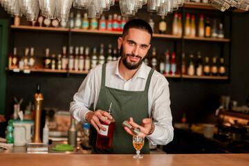 Skilled bartender prepares a cocktail at a stylish bar during a vibrant evening in a bustling city