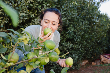 Lady smelling a ripe lemon from the tree, recently picked up