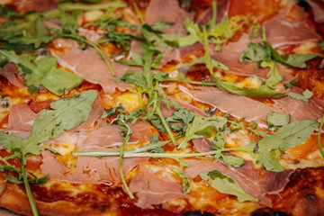 A delicious pizza topped with thin slices of prosciutto, melted cheese, and caramelized onions on a crispy golden crust. The rich colors and textures highlight the mouth-watering ingredients.