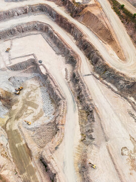 Aerial view looking down into a quarry pit with machinery on the ground