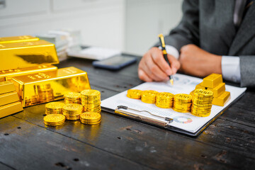 Businessman in suit sits at his desk, holding a shining gold bar. financial charts, the scene...