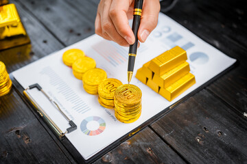 Businessman in suit sits at his desk, holding a shining gold bar. financial charts, the scene...