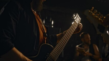 Midsection of two unrecognizable bass guitarists spending time rehearsing with bandmates at recording studio before live performance on stage