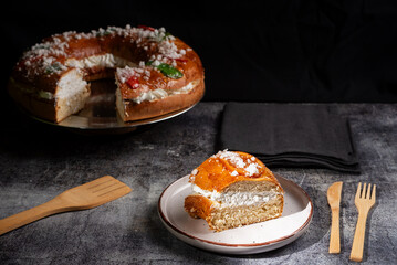 A slice of King`s Cake, a typical sweet used in the celebration of the Three Wise Men, made with sweet dough, decorated with candied fruit and filled with cream.