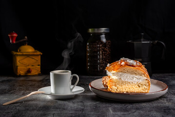 A slice of king`s Cake accompanied by a cup of coffee, a typical sweet used on the feast of the Three Wise Men, made with sweet dough, decorated with candied fruit and filled with cream.