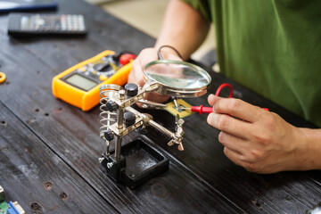 Technician carefully repairs a computer circuit board, using precision tools to address hardware...