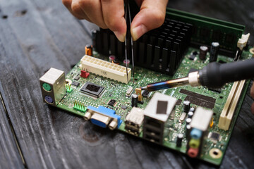 Technician carefully repairs a computer circuit board, using precision tools to address hardware...